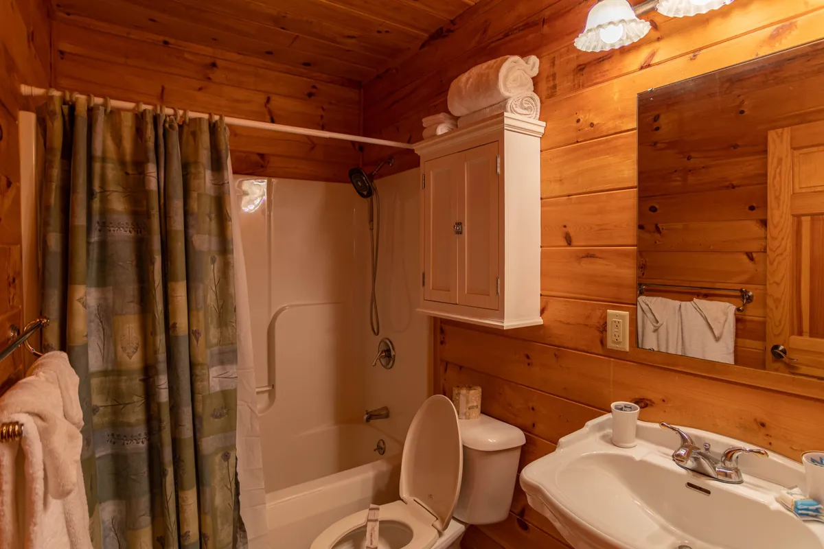 A bathroom with wooden walls, a comfortable bathtub, sink, mirror, and neatly arranged towels. The inviting atmosphere suggests a spa-like experience, perfect for unwinding after an active day.