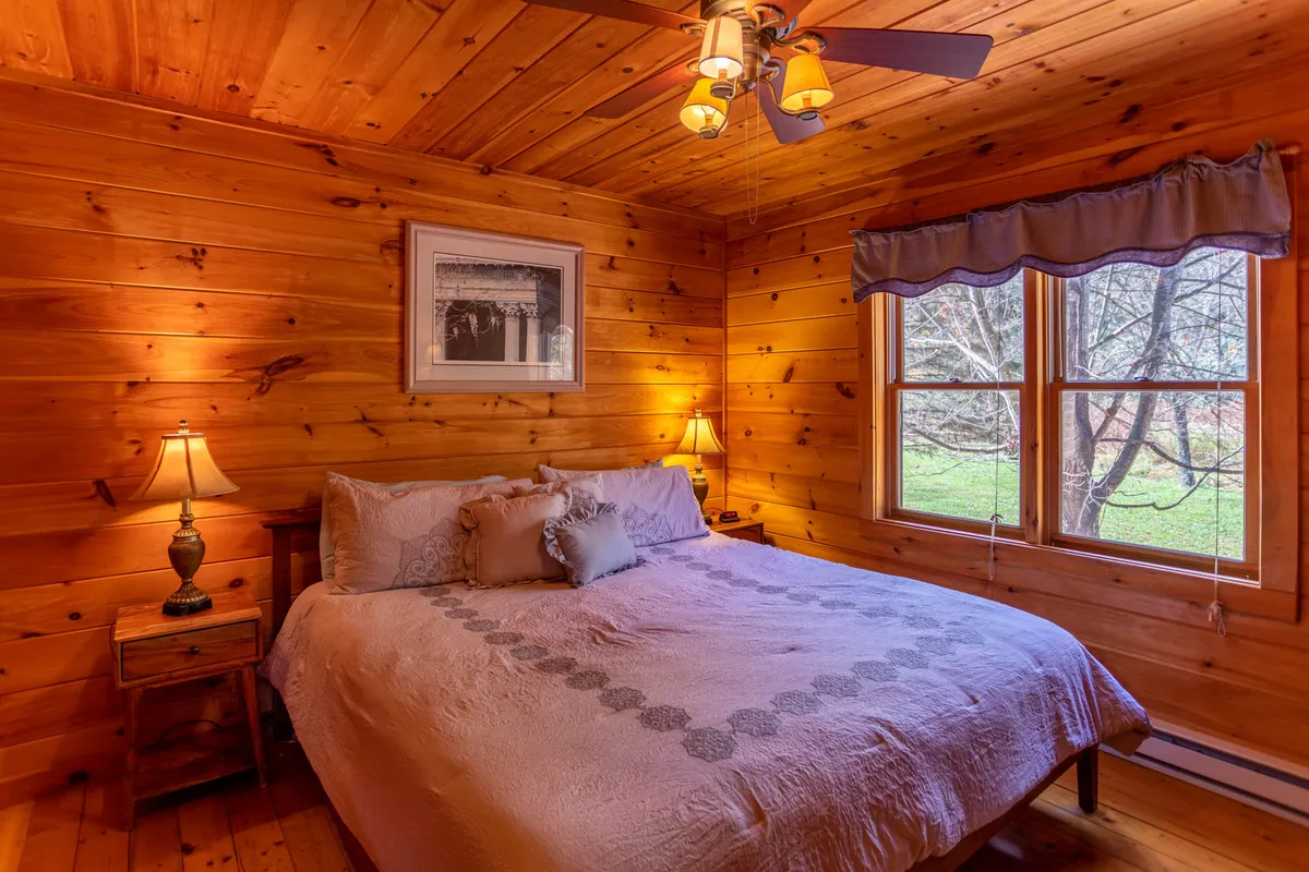 A warmly lit bedroom with a comfortable bed, soft lamps on either side, a window letting in gentle natural light, and tasteful wall art. The space exudes calm and relaxation, ideal for unwinding after a day of outdoor adventure.